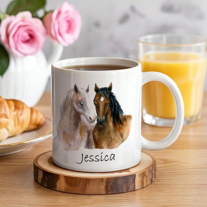 White mug with horse design and 'Jessica' name, placed on a wooden coaster with coffee and croissant in the background.