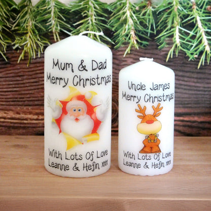 Two Christmas-themed candles with personalized messages in front of a Christmas tree.