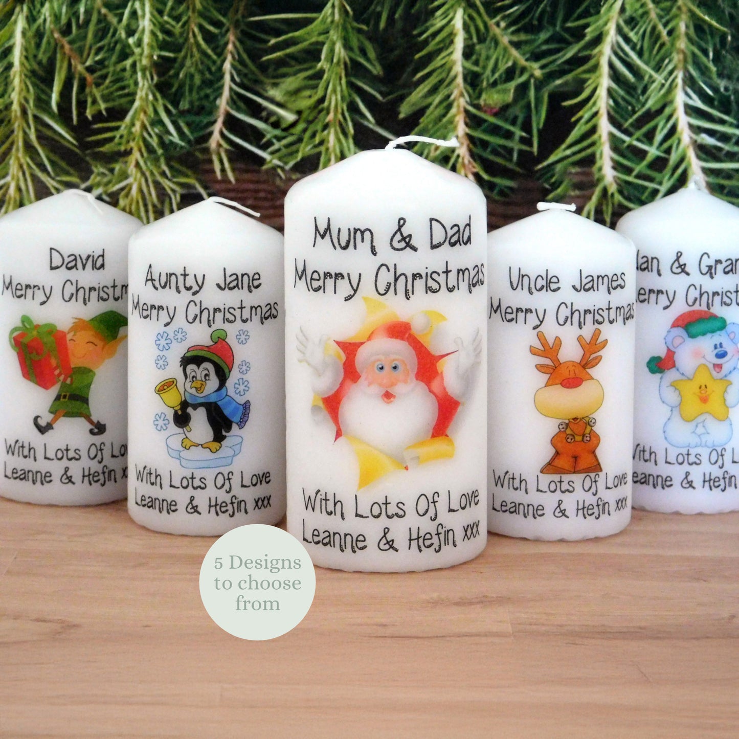 Personalized Christmas candles with cartoon characters and text on a wooden surface with a Christmas tree background.