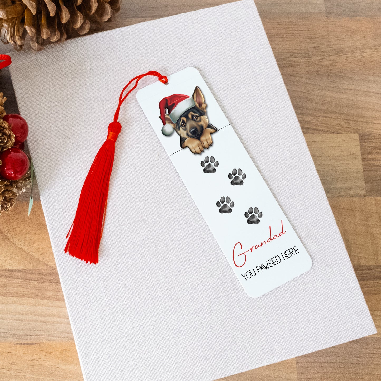 Bookmark with a dog illustration and tassel on a white card, surrounded by Christmas decorations.