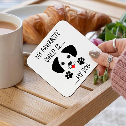 Coaster with dog illustration and text held by a hand on a table with coffee and croissant.