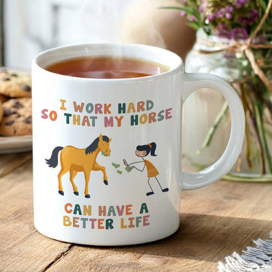 Mug with horse and person illustration and text on a wooden table with tea and cookies.