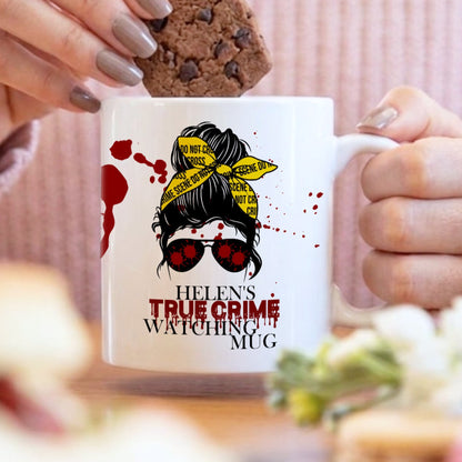 Person holding a mug with a design and text, surrounded by food and a blurred background