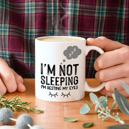 A man holding a mug which says I'm not sleeping I'm resting my eyes