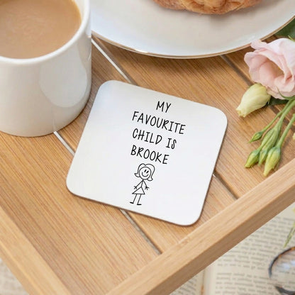 Personalised 'My Favourite Child is Brooke' coaster with stick figure girl design, displayed on a wooden tray alongside a cup of tea and pink flowers