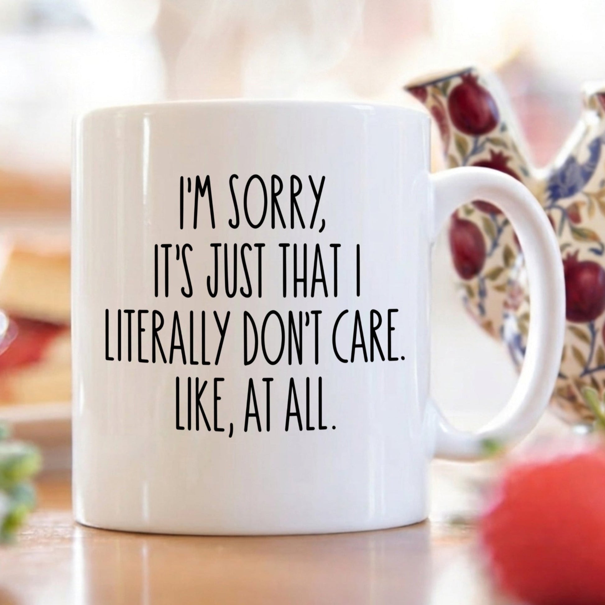 White mug with black text "I'm sorry, it's just that I literally don't care. Like, at all", on a breakfast table with a blurred background