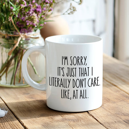 White mug with black text "I'm sorry, it's just that I literally don't care. Like, at all", on a breakfast table with a blurred background