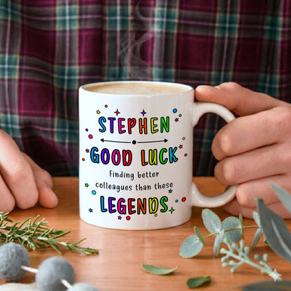 Person holding a mug with colourful text on a wooden table