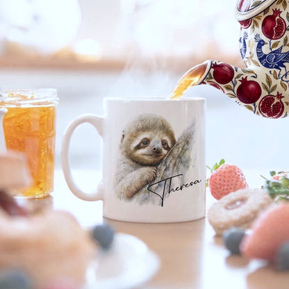Personalised watercolour sloth mug with the name 'Theresa' in elegant script, tea being poured from a floral teapot, surrounded by fresh fruit and berries