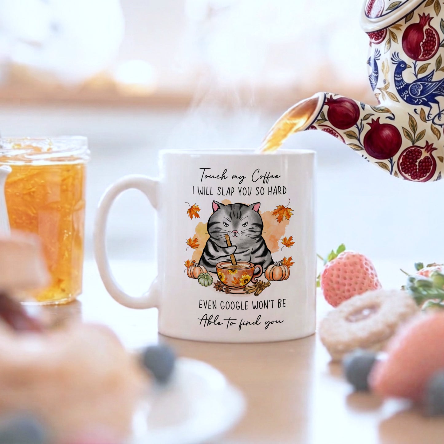 Mug with a cat design and humorous text, surrounded by a blurred breakfast scene.