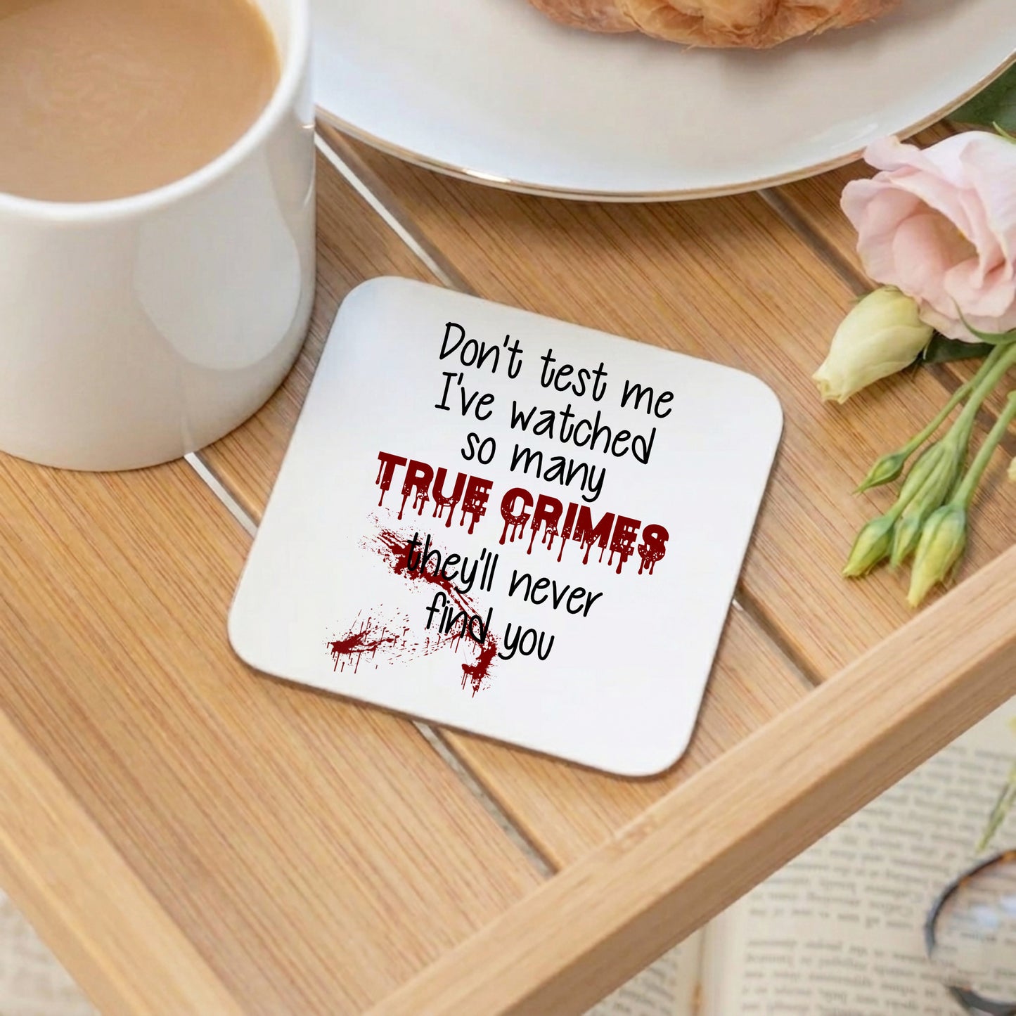 Coaster with text on a wooden table with a cup of coffee and flowers.