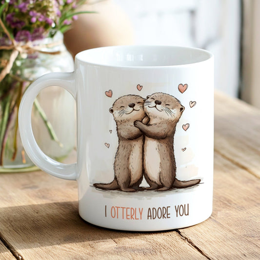 White mug with otter illustration and 'I Otterly Adore You' text on a wooden surface.