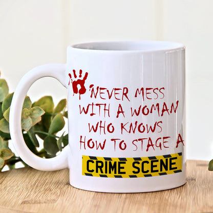 White mug with red and black text and a yellow warning label on a wooden surface with a plant in the background