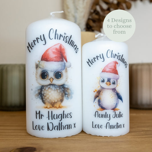 Two Christmas-themed candles with owl and penguin designs on a wooden surface.