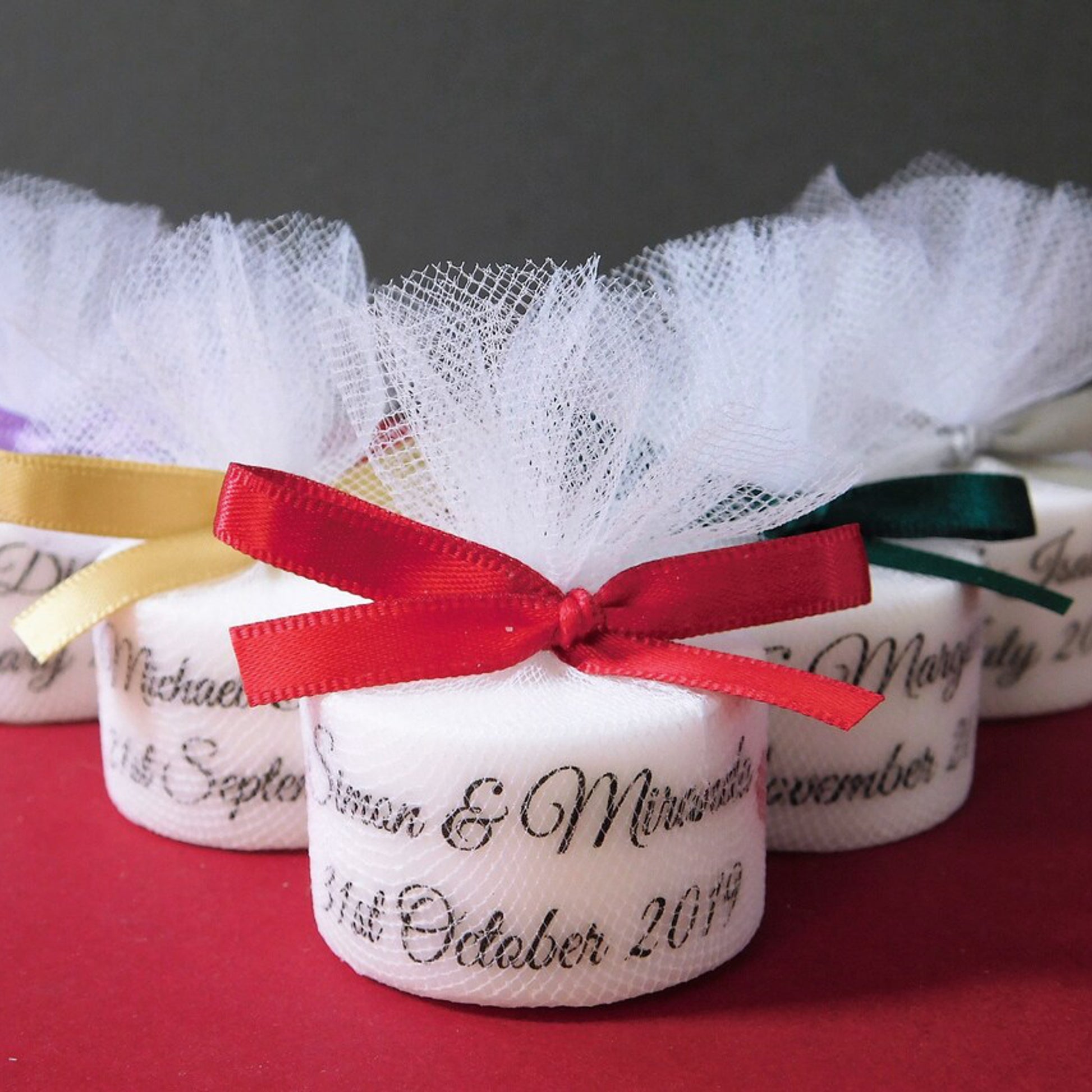 Decorative tealights with personalised inscriptions and ribbons on a red surface