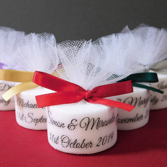 Decorative tealights with personalised inscriptions and ribbons on a red surface