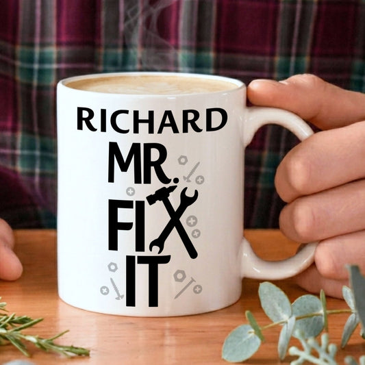 Person holding a mug with 'Richard Mr. Fix It' text and tools graphic on a wooden table.
