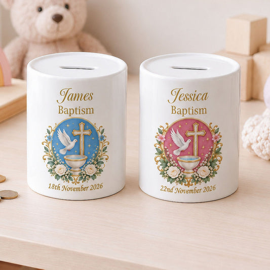 Two personalised ceramic baptism money boxes on a light wood table, decorated with gold text and colourful baptism emblems, styled in a child's nursery with toys and coins.