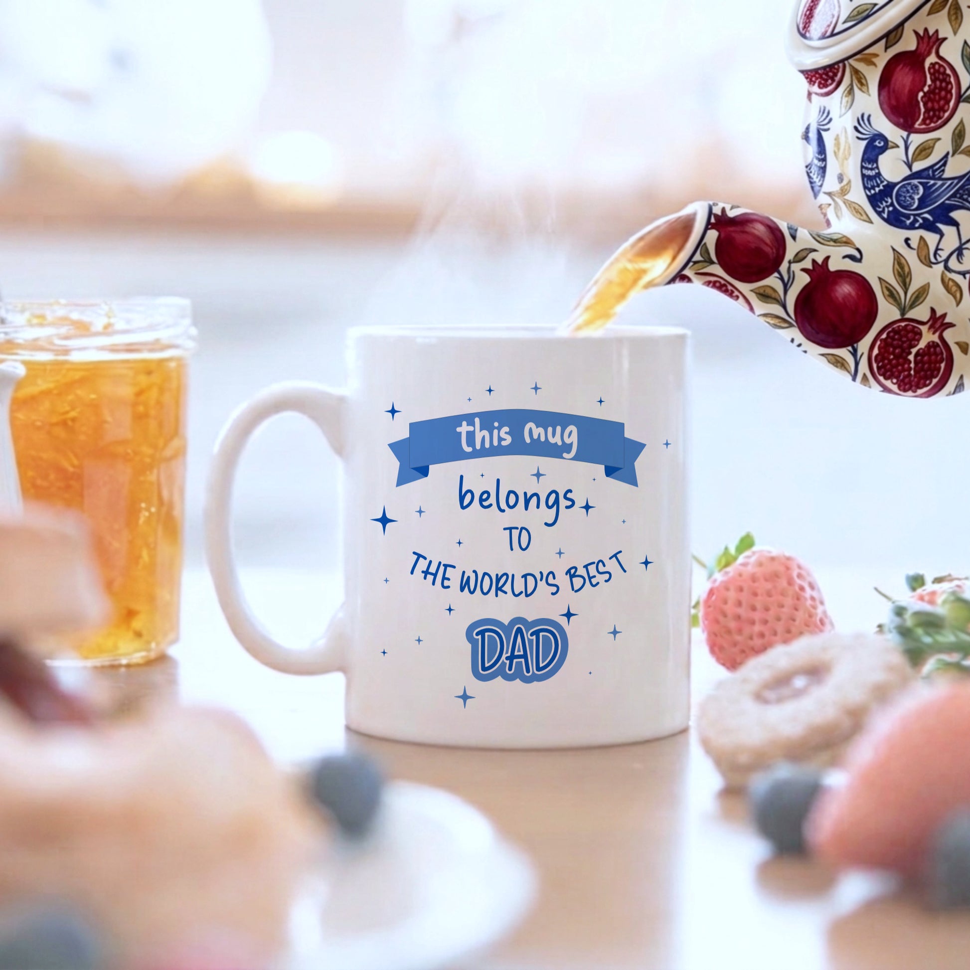 Mug with 'World's Best Dad' text being filled with tea, surrounded by breakfast items.