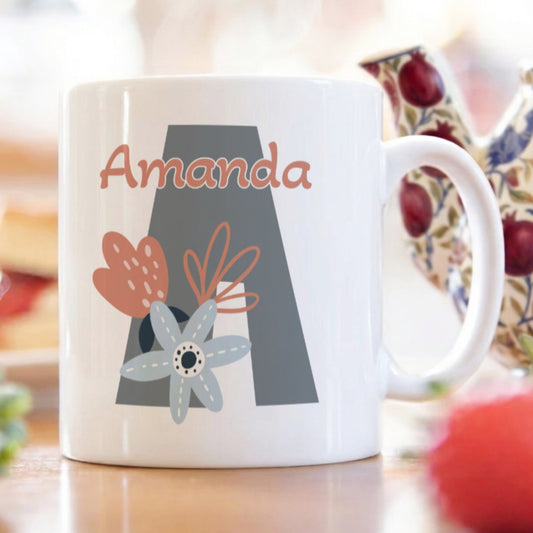 White mug with 'Amanda' and decorative letter 'A' on a blurred background