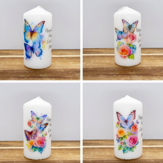 White candle with butterfly and floral design on a wooden surface