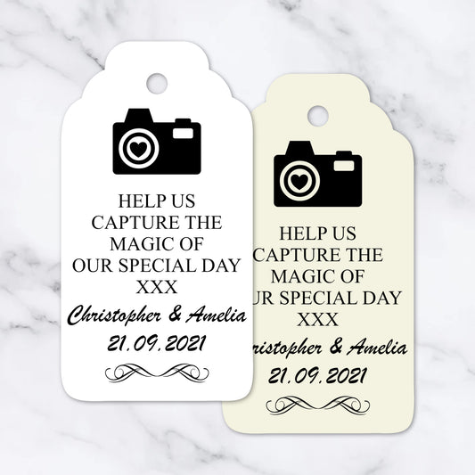 Two wedding favor tags with camera icon and personalized text on a marble background