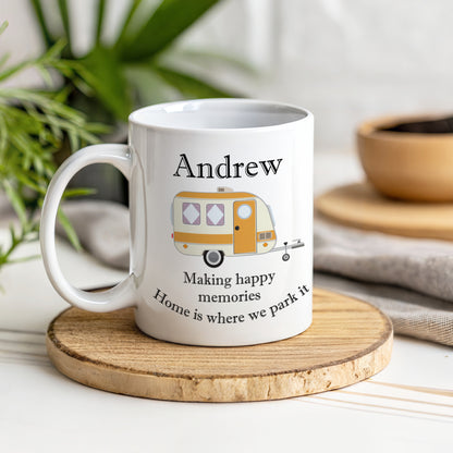 A white mug with a caravan design and the name Andrew on a wooden coaster