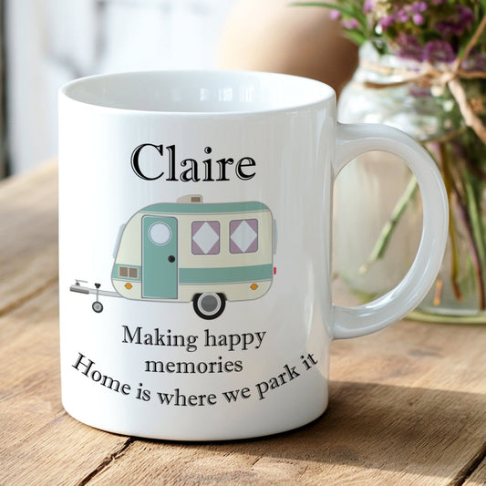 White mug with a camper design and text on a wooden surface with flowers in the background