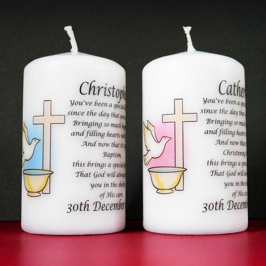 Two white candles with religious designs and text on a black background