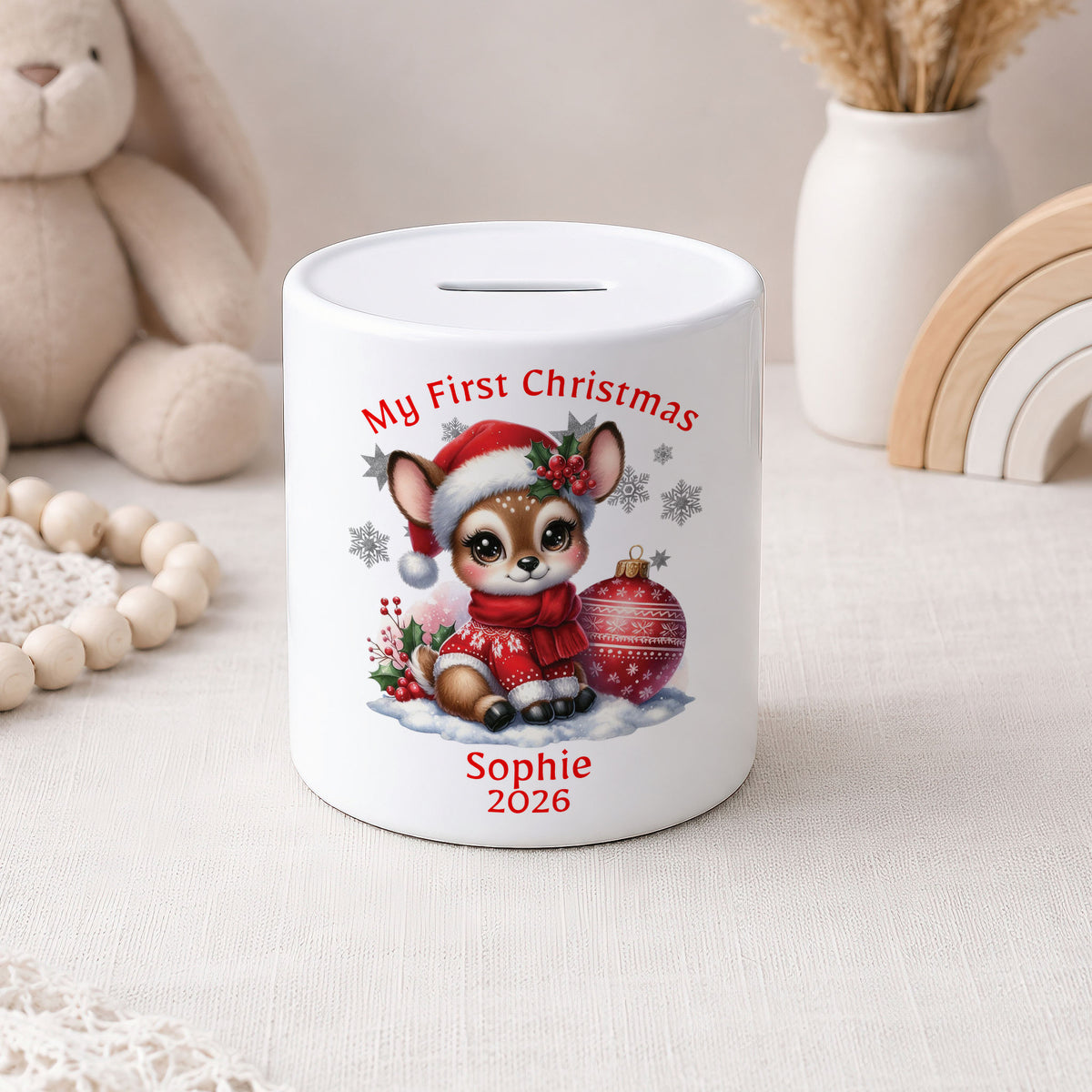 A white ceramic pig bank with a custom Christmas illustration of a chihuahua wearing a Santa hat and scarf, sitting next to a red ornament. The text reads 'My First Christmas' and 'Sophie 2026'.