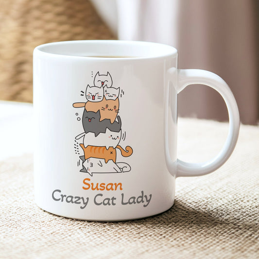 White mug with cat illustration and 'Susan Crazy Cat Lady' text on a textured surface.