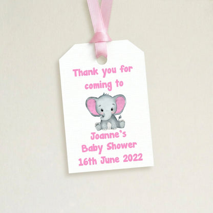 Gift tag with an elephant illustration for a baby shower, featuring text and a pink ribbon.