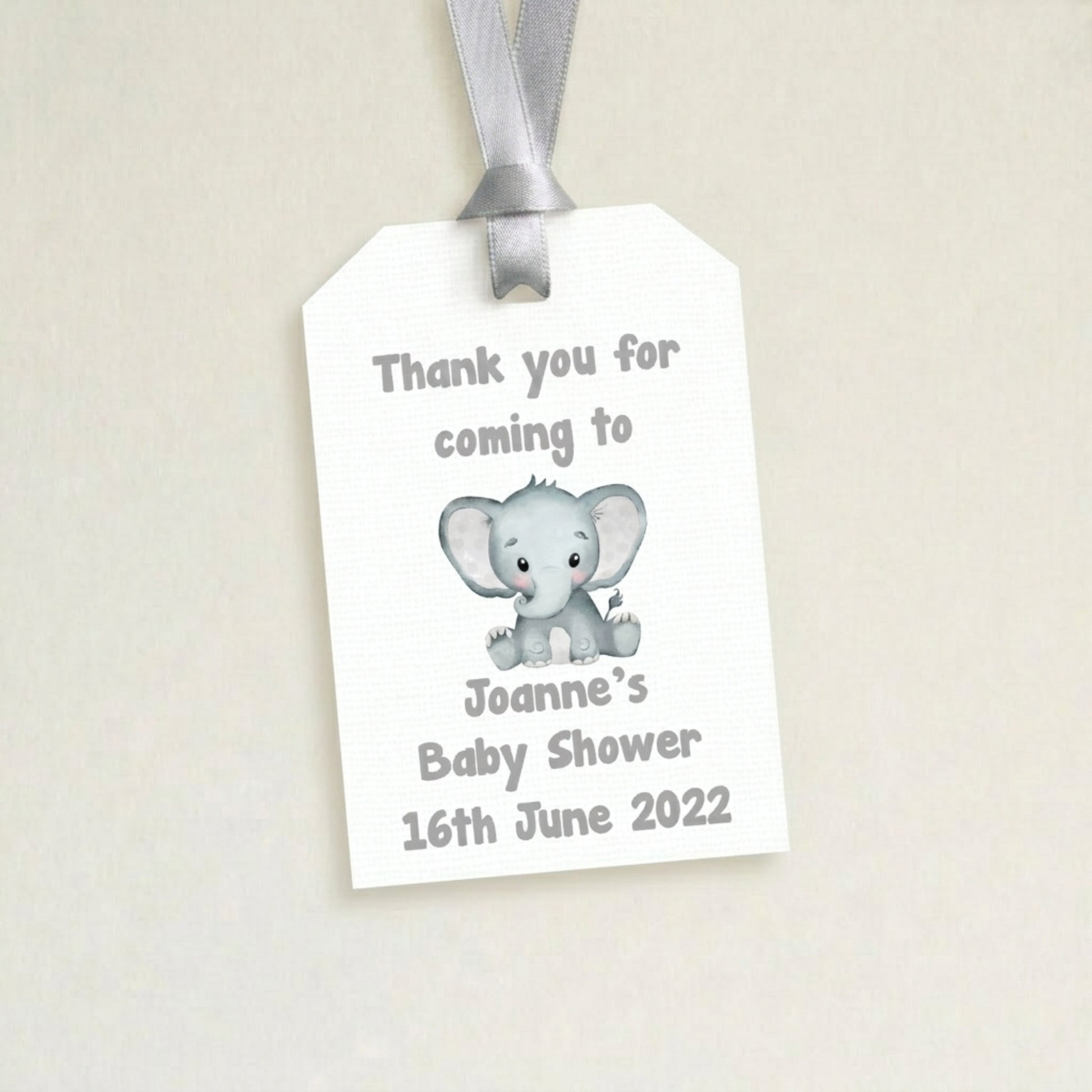 Gift tag with elephant design and baby shower message on a beige background