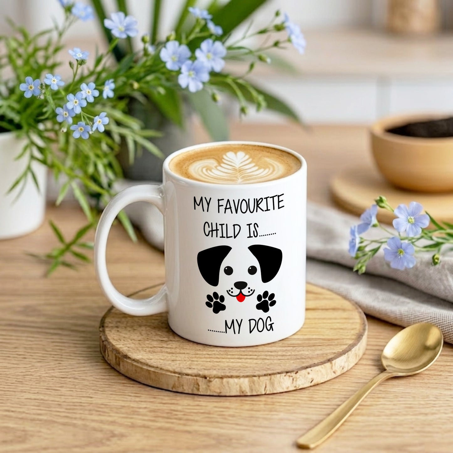 Mug with a dog illustration and text on a wooden coaster with flowers and a bowl in the background