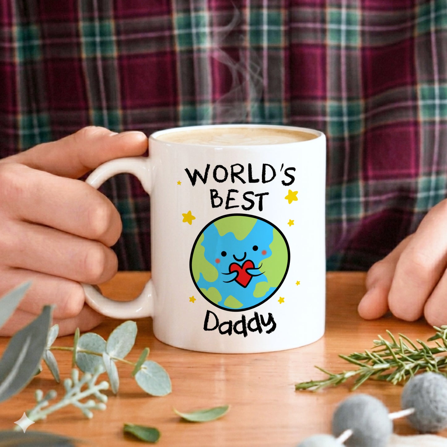 White mug with 'World's Best Daddy' design held by a person, on a wooden table with a plaid shirt background.