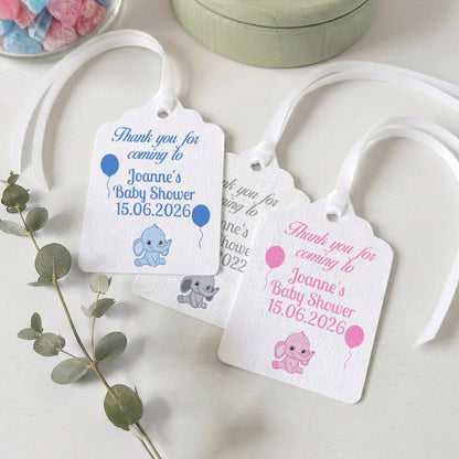Three personalised baby shower gift tags with white ribbons, featuring blue and pink elephant illustrations and text for Joanne's Baby Shower on 15.06.