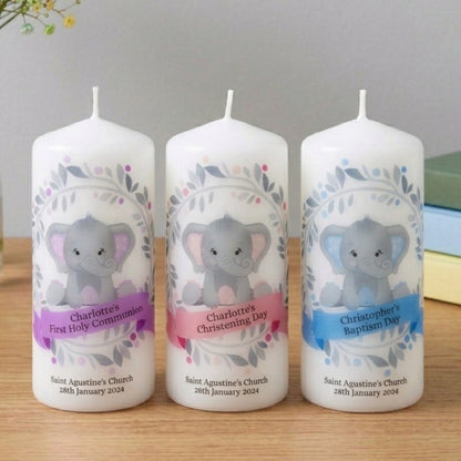 Three personalized candles with elephant designs on a wooden surface.