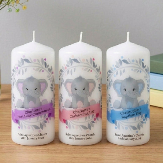 Three personalized candles with elephant designs on a wooden surface.
