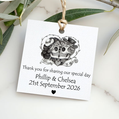 Personalized wedding tag with skull design and text on a marble surface with leaves.