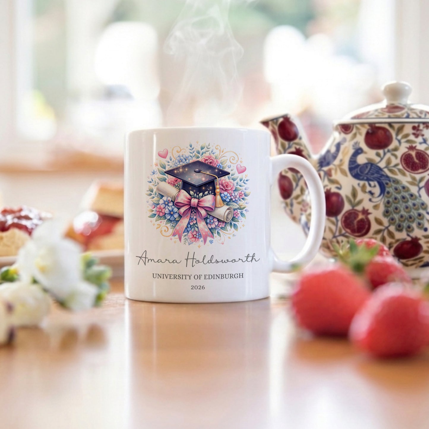 White mug with graduation design and text on a table with tea set and fruits