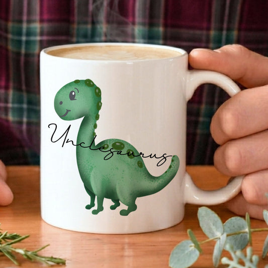 Person holding a mug with a dinosaur design and 'Unclesaurus' text on a wooden table.