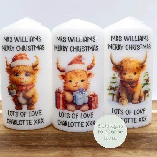 Three personalized candles with a cartoon Highland cow design, featuring the text 'Mrs Williams Merry Christmas' and 'Lots of love Charlotte XXX'.
