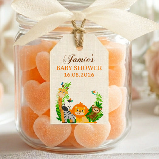 Jar of orange gummy bears with a personalized label for a baby shower, surrounded by flowers.