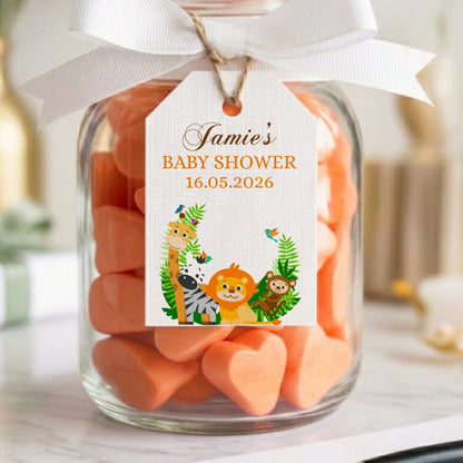 Jar of orange heart-shaped candies with a baby shower tag on a table.