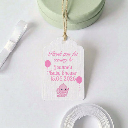 A personalised baby shower thank you gift tag with a pink elephant and balloon design, hanging from a twine string. The white textured tag features pink text reading 'Thank you for coming to Joanne's Baby Shower 15.