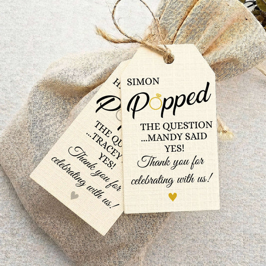 Personalised burlap gift tags tied to a burlap bag, printed with custom names and wedding-themed text on a neutral fabric background.