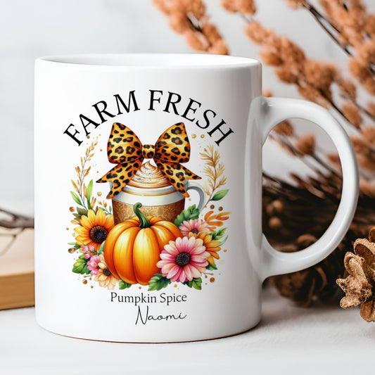 White mug with pumpkin spice design featuring a leopard print bow, pumpkin, and flowers on a white background.