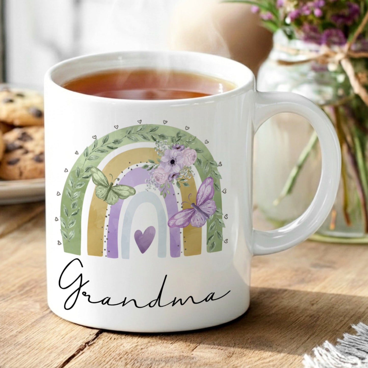 White mug with 'Grandma' design on a wooden table with tea and cookies.