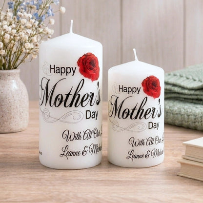 Two white candles with 'Happy Mother's Day' text and red roses on a wooden surface.