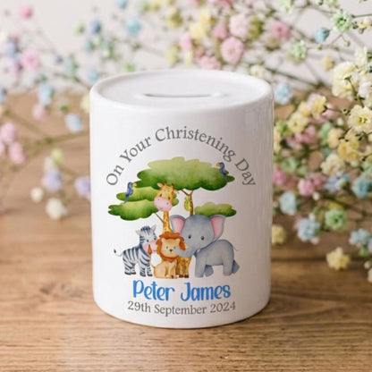 White money box with cartoon animals and personalised text on a wooden surface with flowers in the background